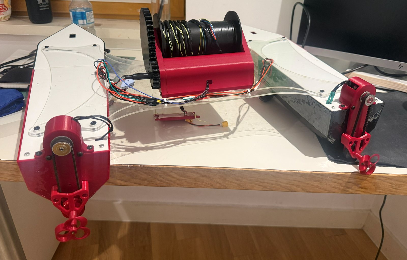Fully assembled catamaran on a desk, showing the winch spool and belt-driven propulsion pods