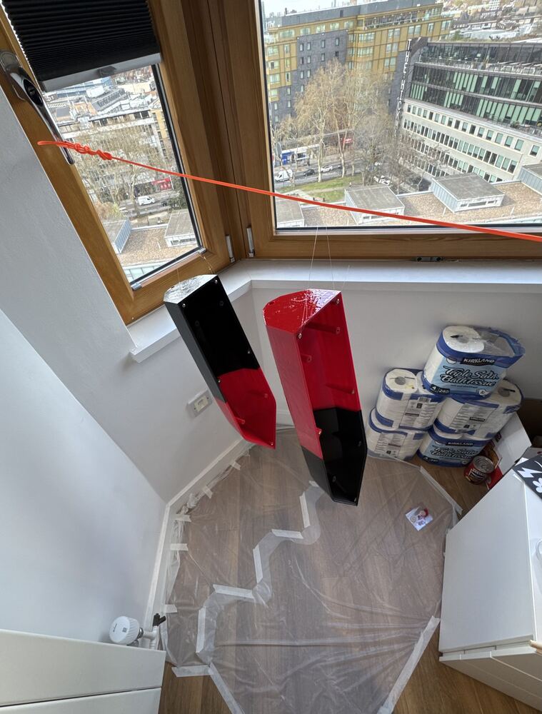 Painted red and black hull panels hung to dry over a drop cloth