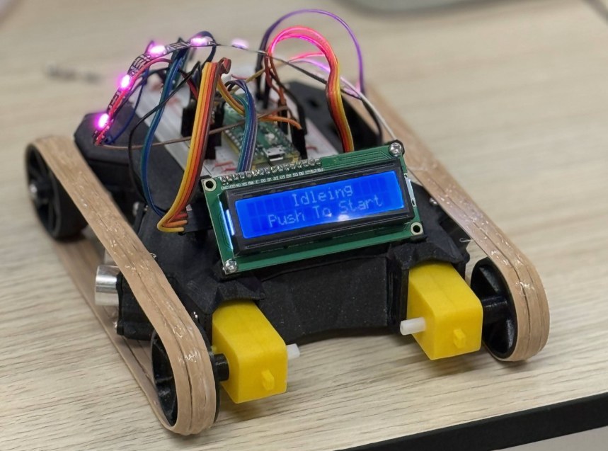 The finished maze-solving robot with tank tracks, an LCD status screen, and a Raspberry Pi Pico